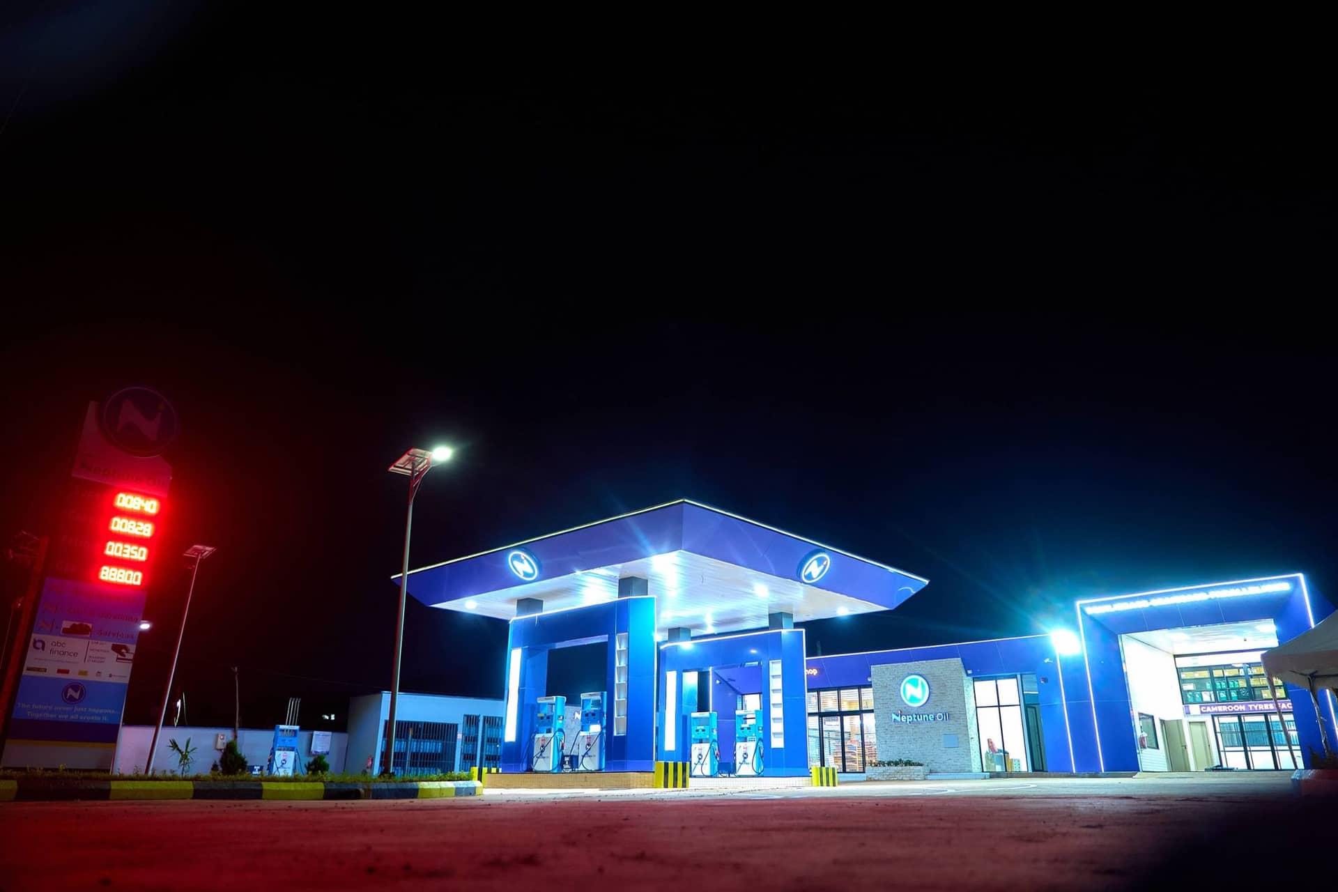 Station Neptune Oil illuminée de nuit, totem des prix au premier plan