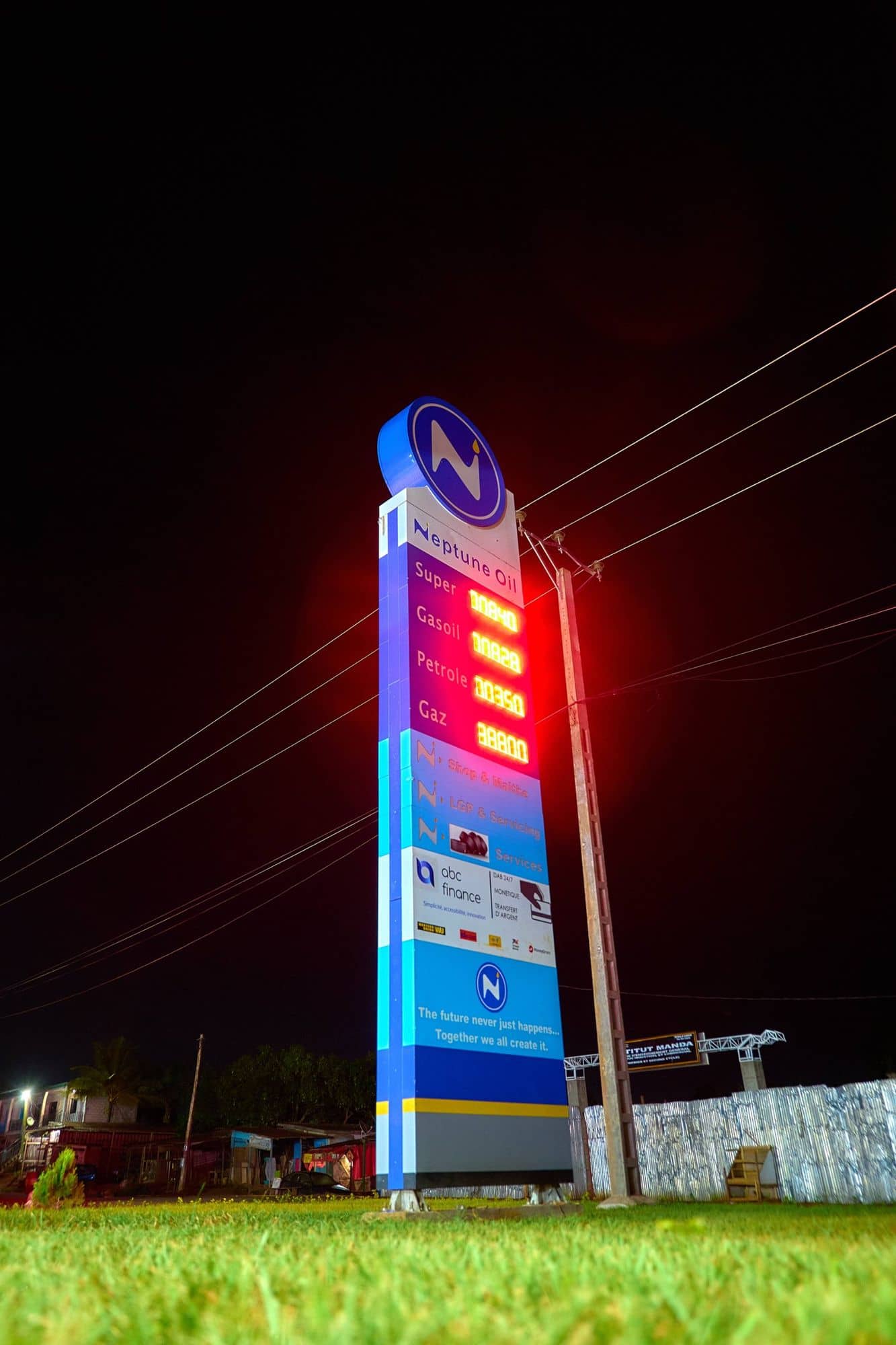 Totem Neptune Oil illuminé avec les prix, de nuit